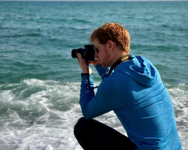 a student takes a photo of the ocean on the beach in Barcelona